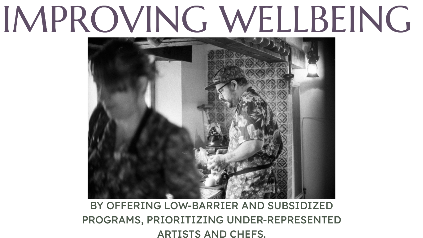 a black and white image of two chefs one in focus one blurry/in the foreground - both in floral aprons - tiles in the kitchen which is rustic - both at work